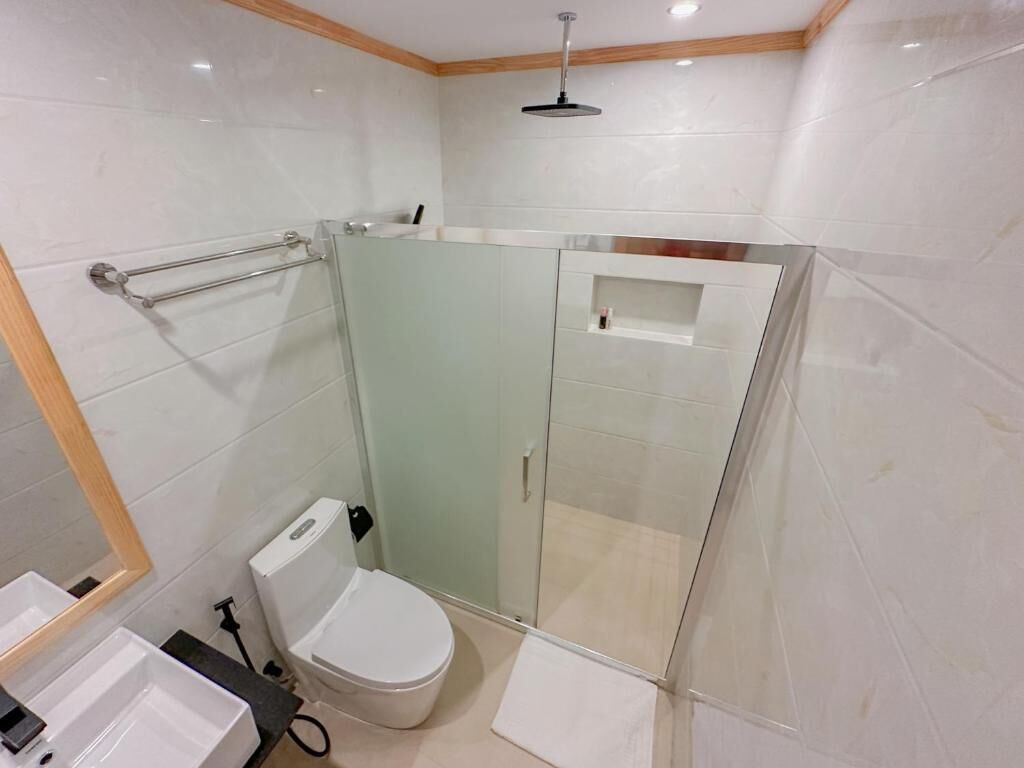 A modern bathroom with a glass shower enclosure, a toilet, and a sink.