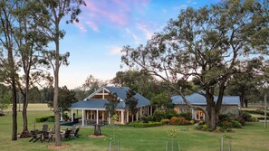 A two-story building with a covered patio area, surrounded by trees and a well-maintained lawn. - Brokenback Homestead (Pokolbin)