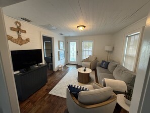 Un salon comprenant un téléviseur, un canapé, une table basse et une ancre décorative accrochée au mur.