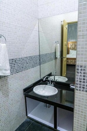A bathroom with a white sink, black countertop, and tiled walls.
