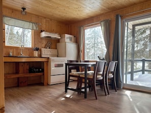 Ein Holzblockhaus-Interieur mit Küchenzeile, Esstisch und Stühlen.