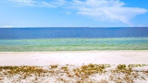 Ein Strand mit klarem türkisblauem Wasser und einem sandigen Ufer.