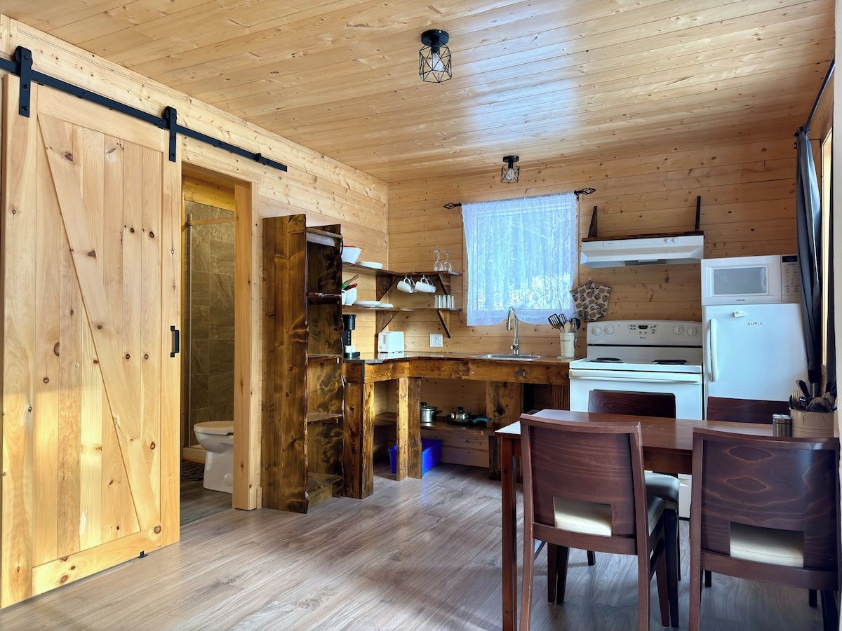 Et træinteriør med et tekøkken, inklusiv komfur, køleskab og spisebord med stole.