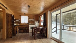 A wooden interior with a kitchen, dining area, and large windows.