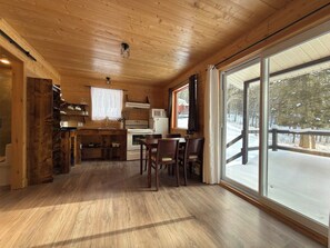 A wooden interior with a kitchen, dining area, and large windows.