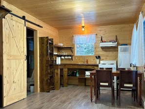 A wooden interior with a kitchen area, dining table, and chairs.