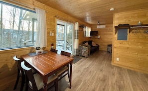 L’intérieur d’un chalet en bois comprend une table à manger, des chaises, un canapé et un téléviseur.
