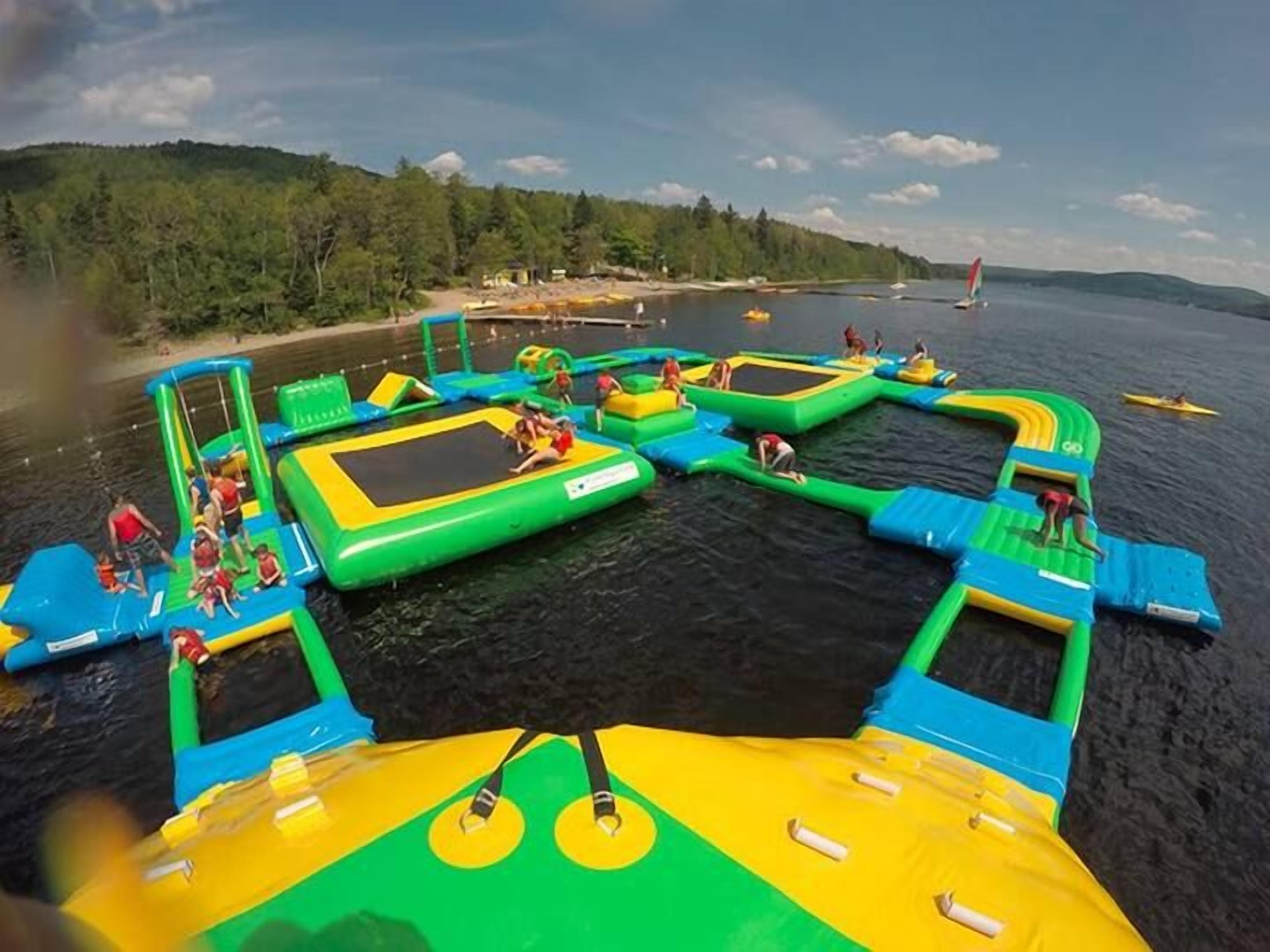 An outdoor water park with inflatable play structures and a body of water.