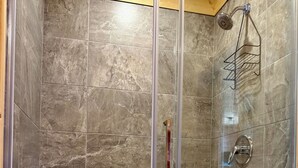 A shower enclosure with a glass door, a showerhead, and a metal rack.