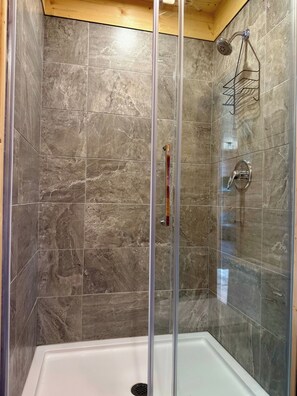 A shower enclosure with a glass door, a showerhead, and a metal rack.
