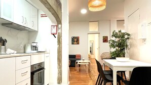 Een moderne keuken met witte kasten, een ingebouwde oven en een eethoek met een tafel en stoelen.