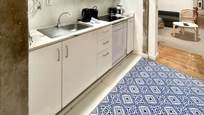 Een compacte keuken met witte kasten, een ingebouwde oven en een koffiezetapparaat.