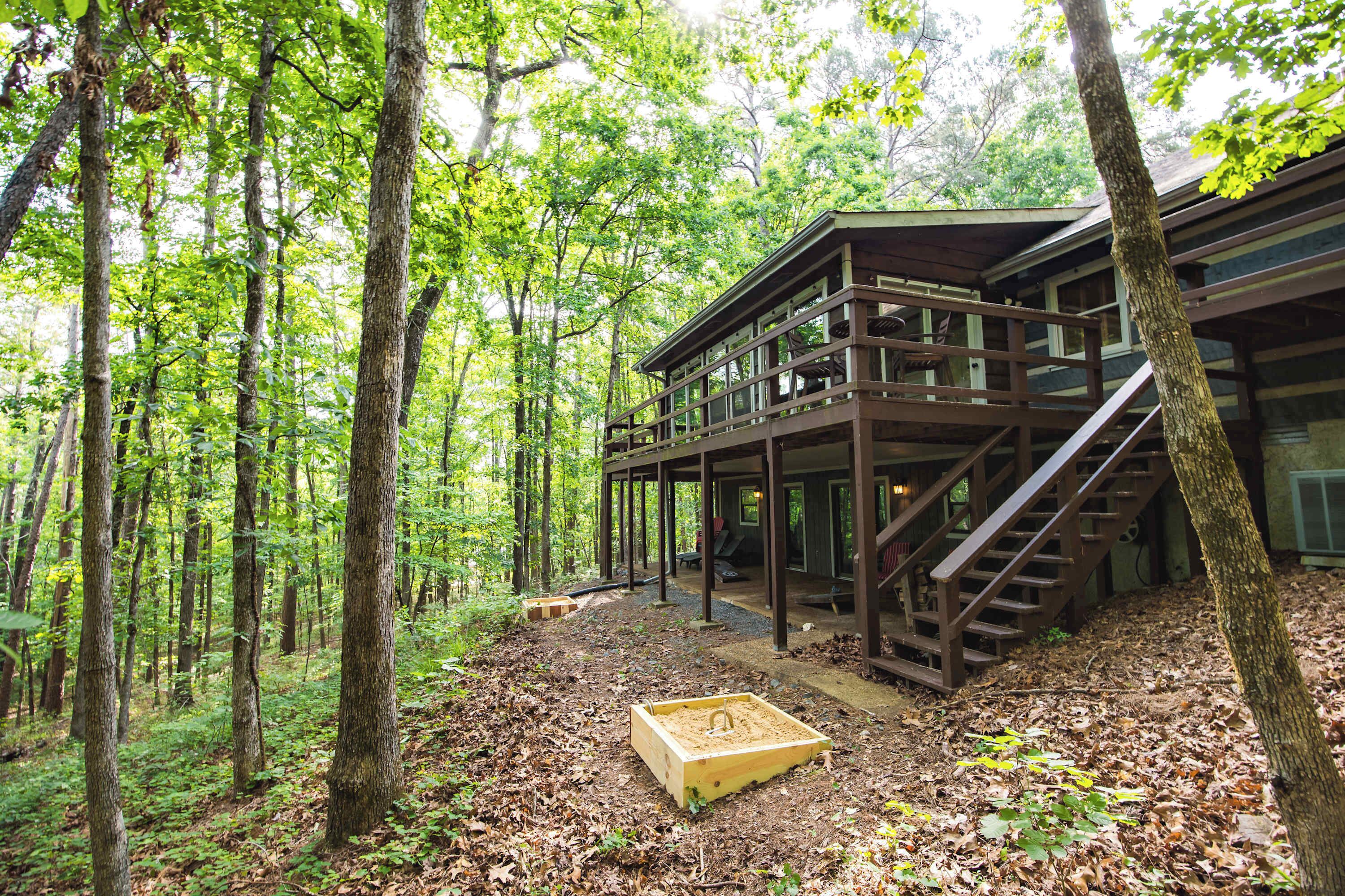 Une cabane en bois dotée d’une terrasse et d’un escalier, entourée d’une forêt.