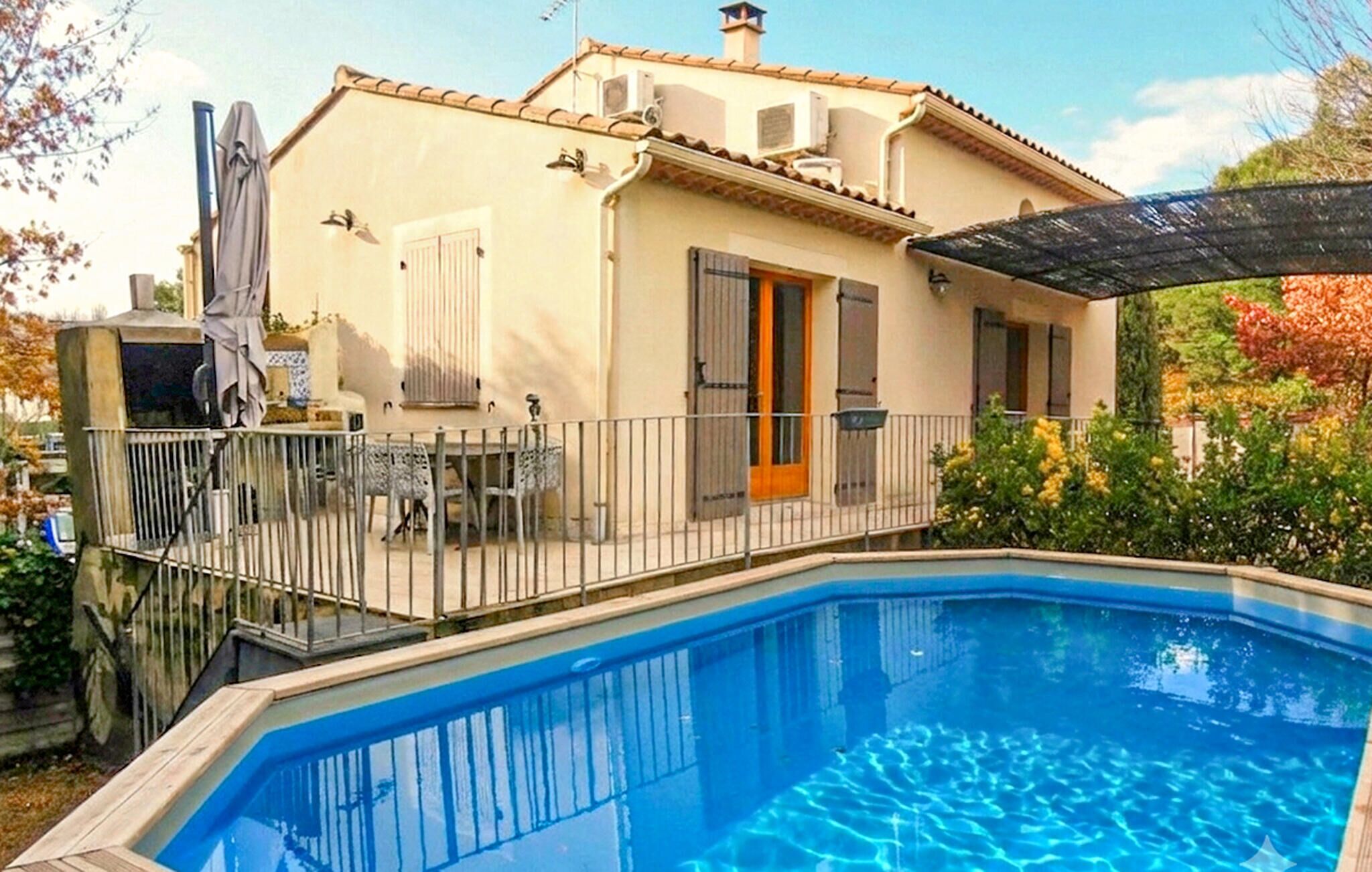 A house with a swimming pool, a covered patio, and a garden.