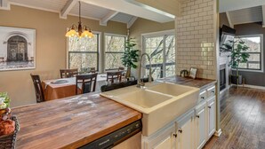 A kitchen with a large island, wooden countertops, and a built-in dishwasher. There are multiple windows providing natural light and a view of the outdoors. - Mountain Views, Peaceful Waterfall 3 King Bedrooms (Pickens)