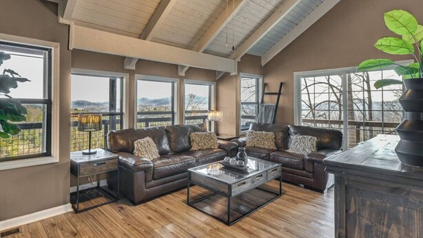 A spacious living room with a large sectional sofa, a glass coffee table, and a view of the outdoors through large windows. - Mountain Views, Peaceful Waterfall 3 King Bedrooms (Pickens)