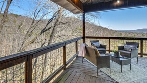 A covered outdoor deck with wicker furniture and a view of a mountainous landscape. - Mountain Views, Peaceful Waterfall 3 King Bedrooms (Pickens)