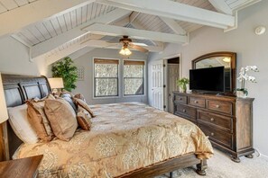 A bedroom with a large bed, a wooden dresser, a television, and a ceiling fan. - Mountain Views, Peaceful Waterfall 3 King Bedrooms (Pickens)