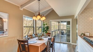 A dining area with a table set for six, a chandelier, and a view of the outdoors through large windows. - Mountain Views, Peaceful Waterfall 3 King Bedrooms (Pickens)