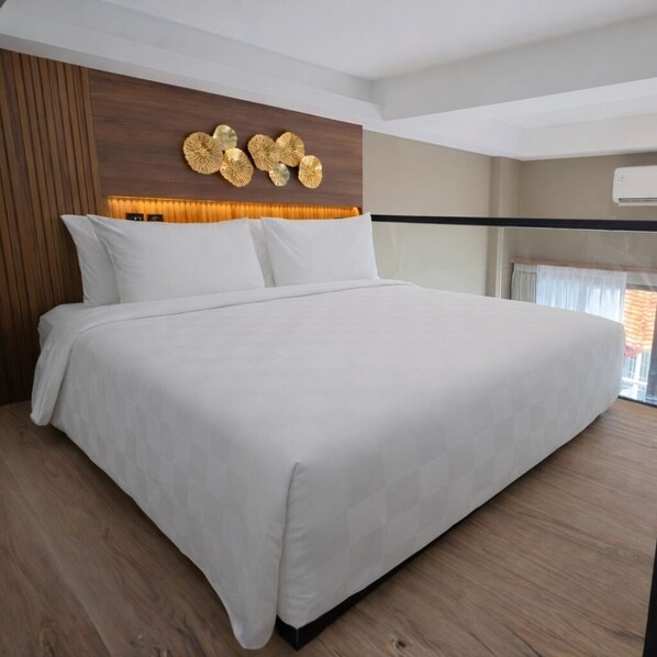 A modern hotel room with a large bed, wooden paneling, and a decorative wall piece. - JJ JIVANA BALI (Tibubeneng)