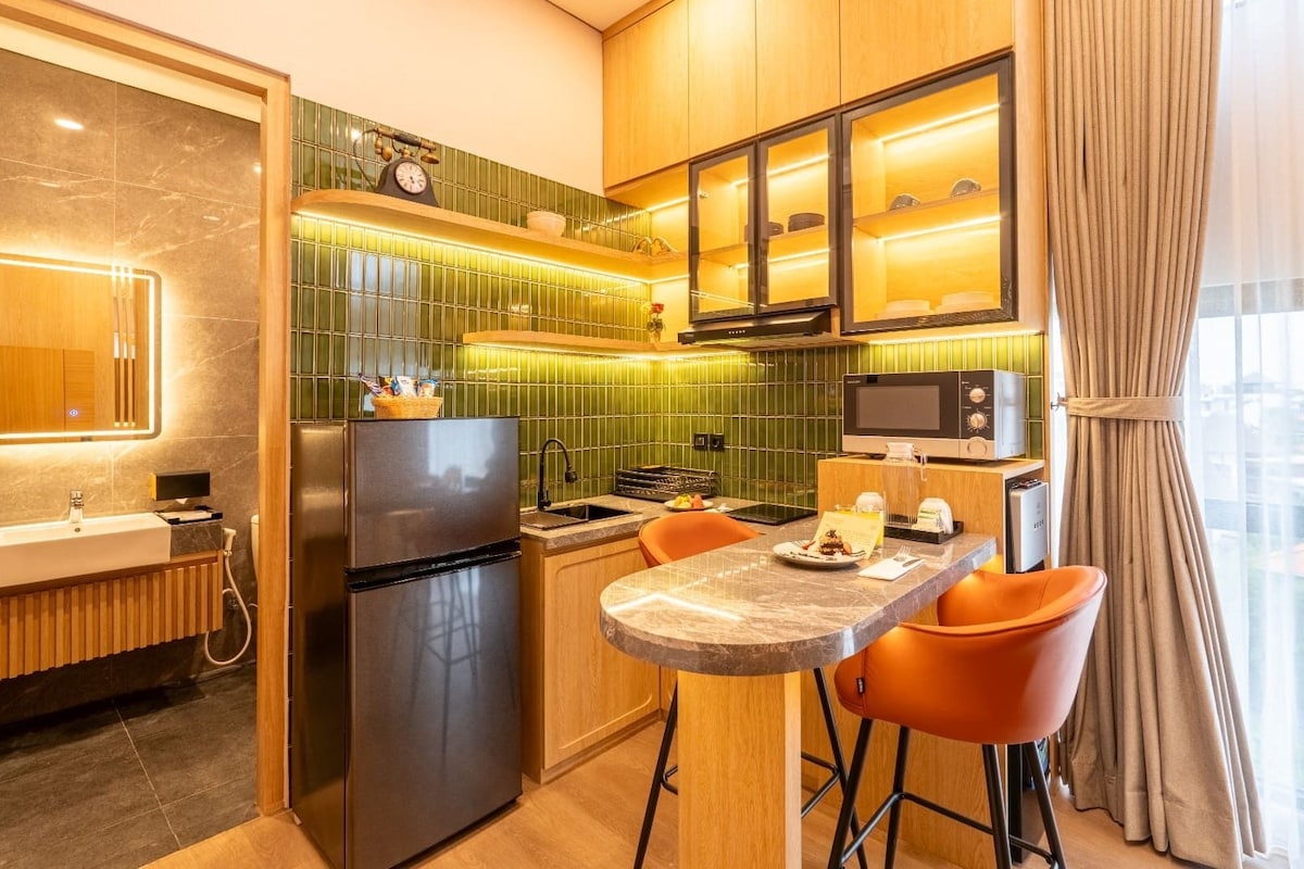 A compact kitchen with a refrigerator, microwave, and a small dining area with two chairs.