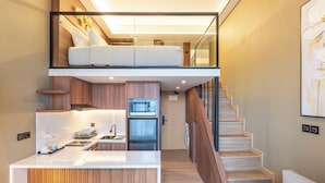 A modern kitchen with a counter, bar stools, and a dining area. - JJ JIVANA BALI (Tibubeneng)