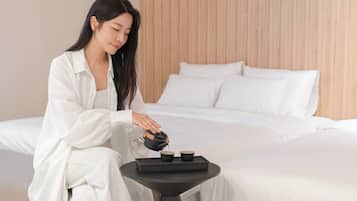 Uma pessoa servindo chá em uma xícara sobre uma mesinha em um quarto de hotel.