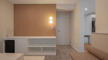 A modern interior with a wooden panel wall, a white console table, a seating area with a patterned cushion, and a clothing rack.