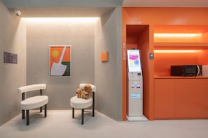 Un kiosque d’enregistrement automatisé, deux chaises, un four à micro-ondes et un panneau indiquant « Enregistrement automatisé ».