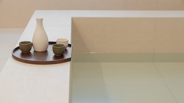 A table with a white vase and two green cups on a tray.