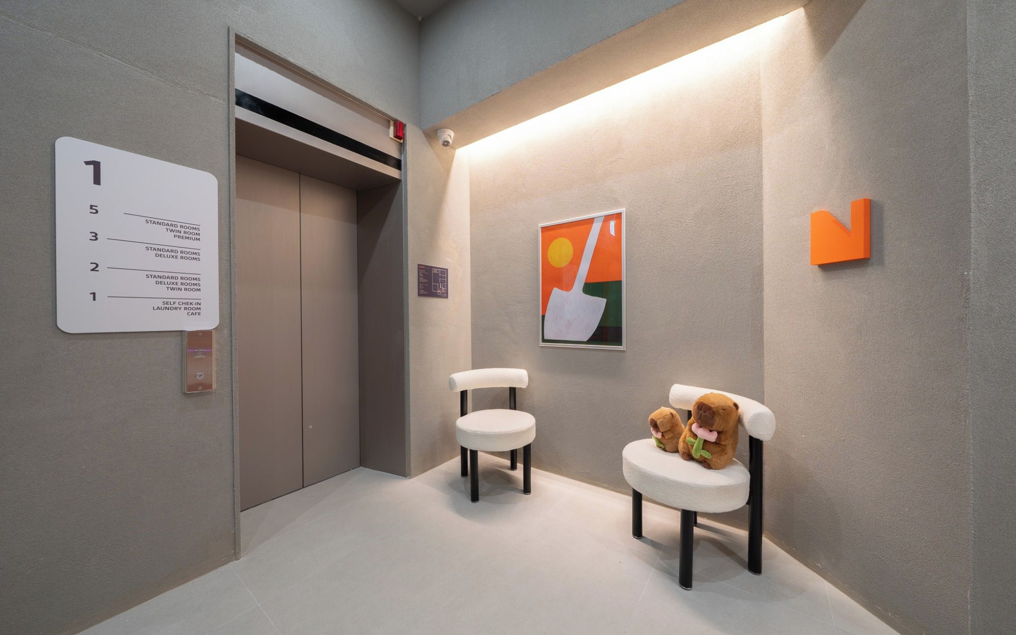 An elevator with a sign indicating room types and a self-check-in laundry room cafe.