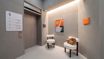 An elevator with a sign indicating room types and a self-check-in laundry room cafe.