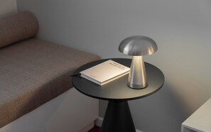 Una mesa redonda con una lámpara metálica y un libro titulado 'Palabras para la bella mujer'.