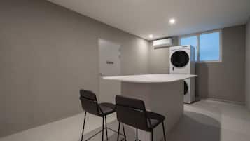A compact kitchen with a built-in washing machine, a small bar area with stools, and a door marked 'Staff Only'.