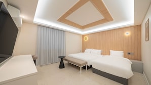A modern hotel room with a large bed, a desk, and a bench.