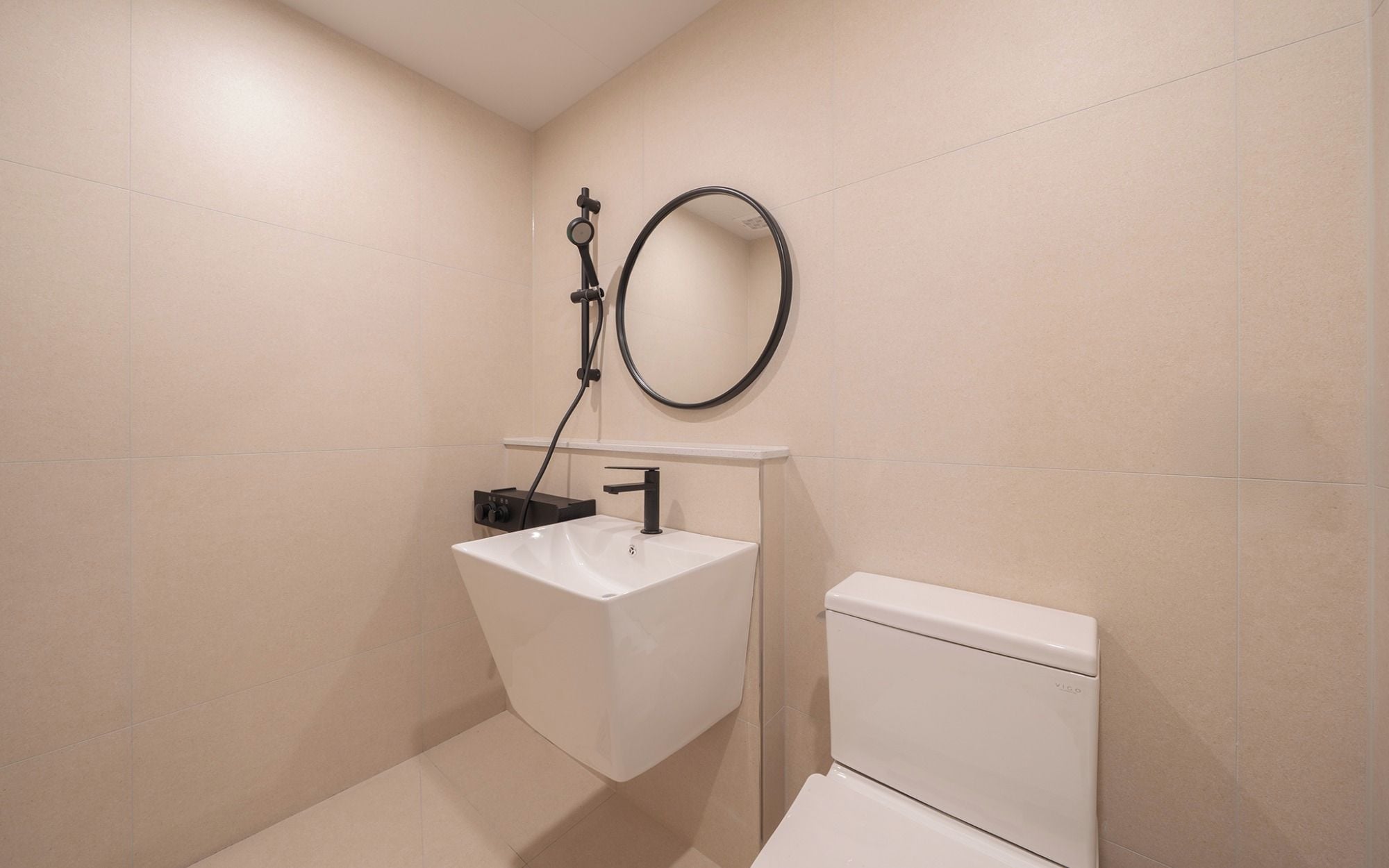 A bathroom with a white sink, a toilet, and a round mirror on the wall.
