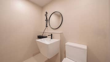 A bathroom with a white sink, a toilet, and a round mirror on the wall.