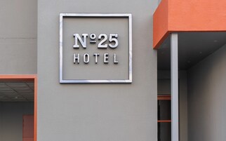 Señal de hotel con el número 25 y la palabra 'HOTEL' en la fachada de un edificio.