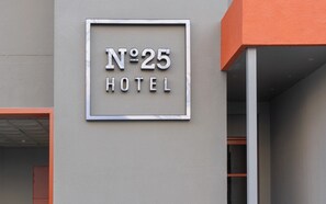 Une enseigne d'hôtel avec le numéro 25 et le mot « HÔTEL » sur la façade d'un immeuble.
