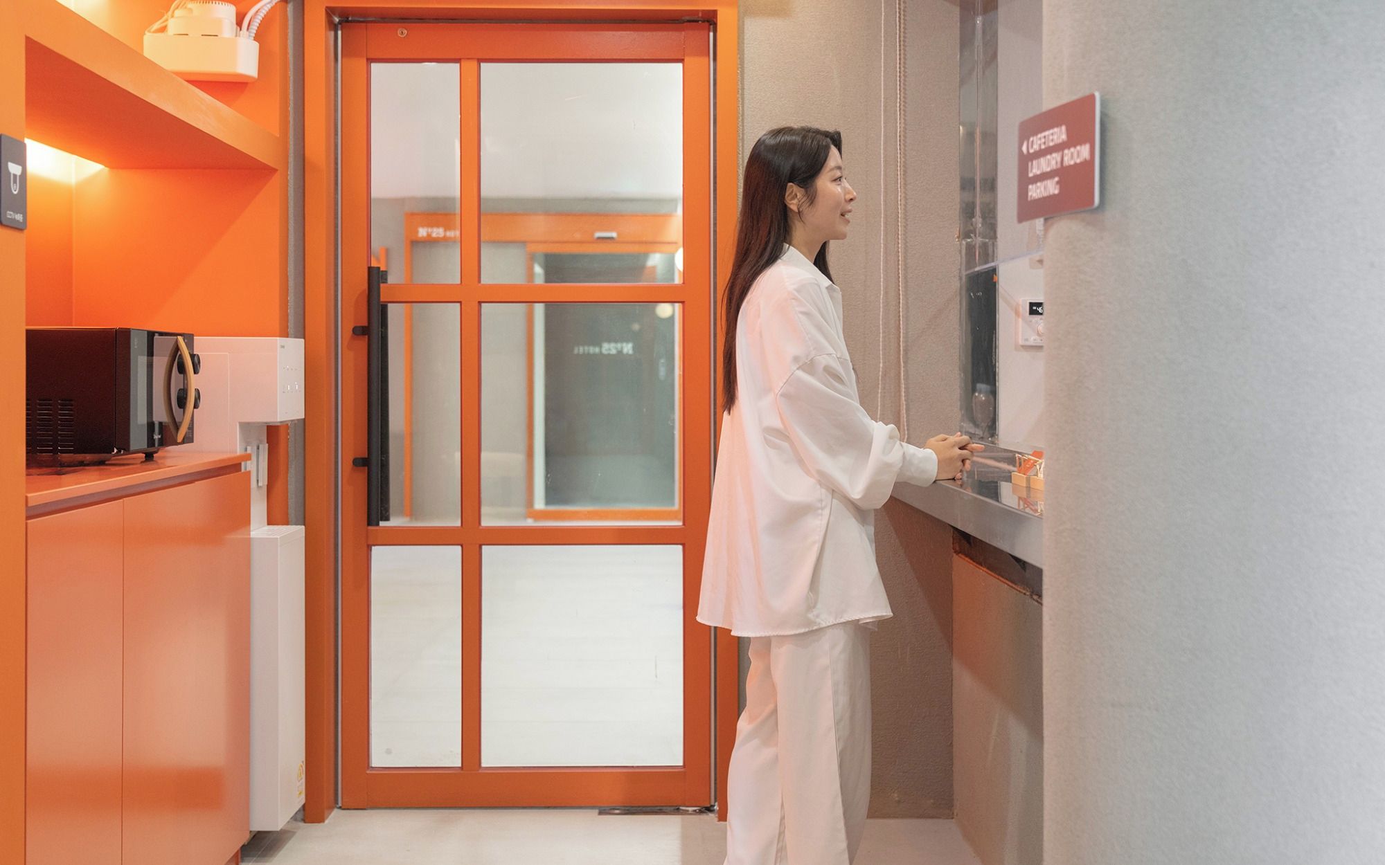 A person at a reception desk in a hotel lobby with a sign indicating a laundry room.