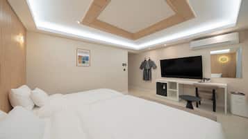 Una habitación de hotel moderna con una cama grande, un televisor de pantalla plana, un escritorio con silla y un espejo.