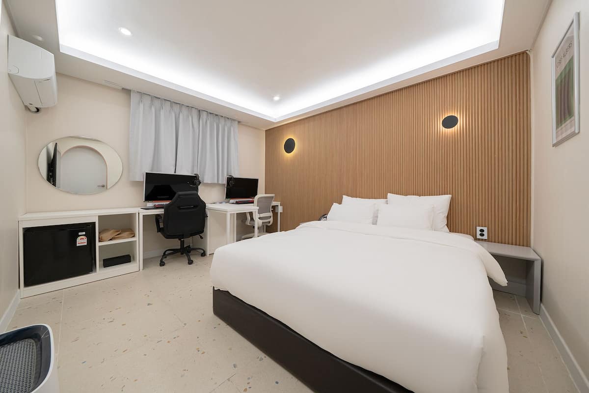 Habitación de hotel con cama, escritorio, silla y un refrigerador pequeño.
