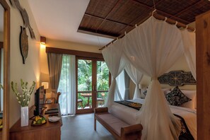 A room with a bed under a canopy, a sofa, a desk with a lamp, and a view of greenery outside. - The Compass Rose Ubud (Ubud)