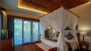 Una cama con dosel, lámparas de noche, un banco de madera y vistas al exterior a través de amplios ventanales.