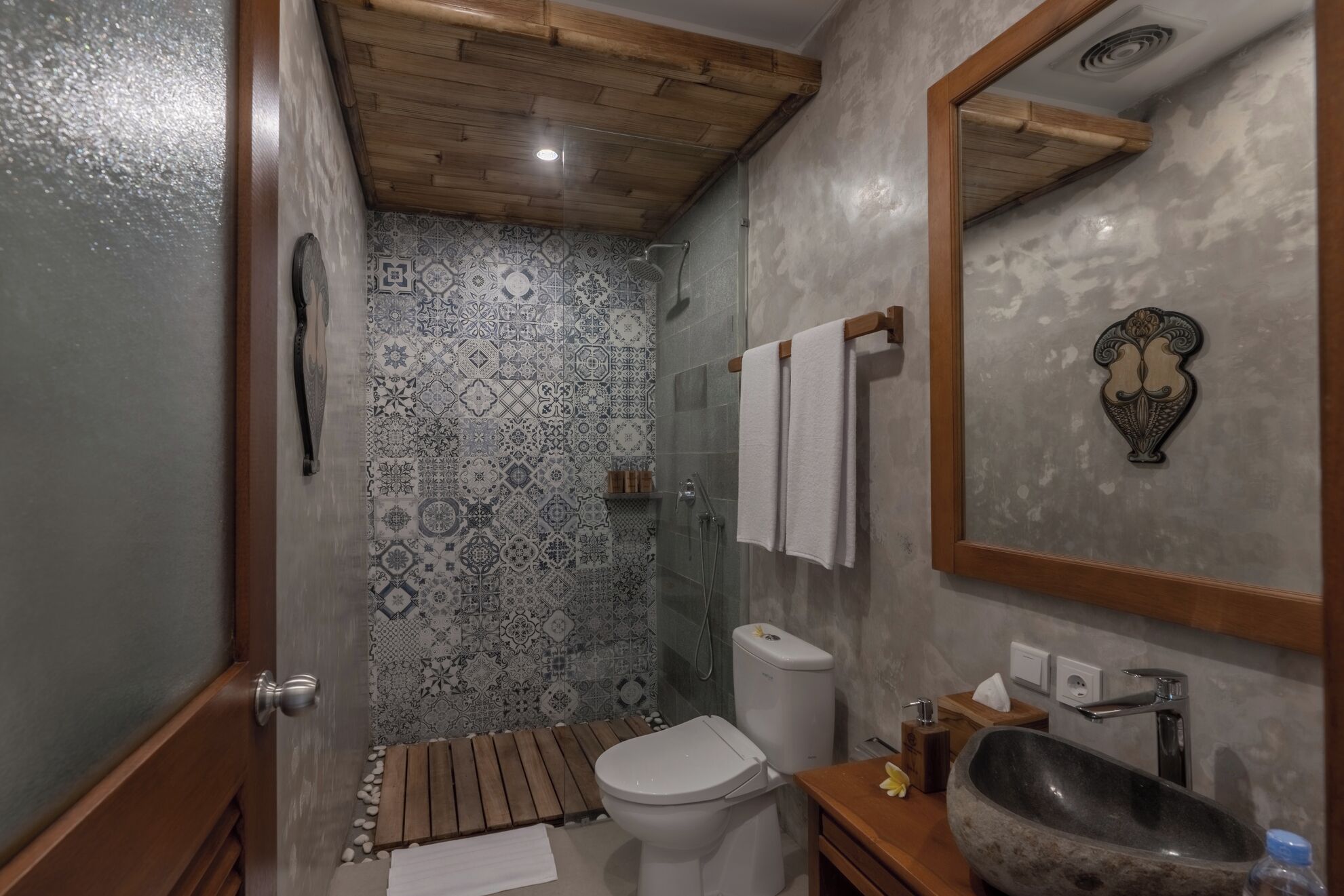 Un baño con ducha, inodoro, lavamanos y un espejo con marco decorativo.