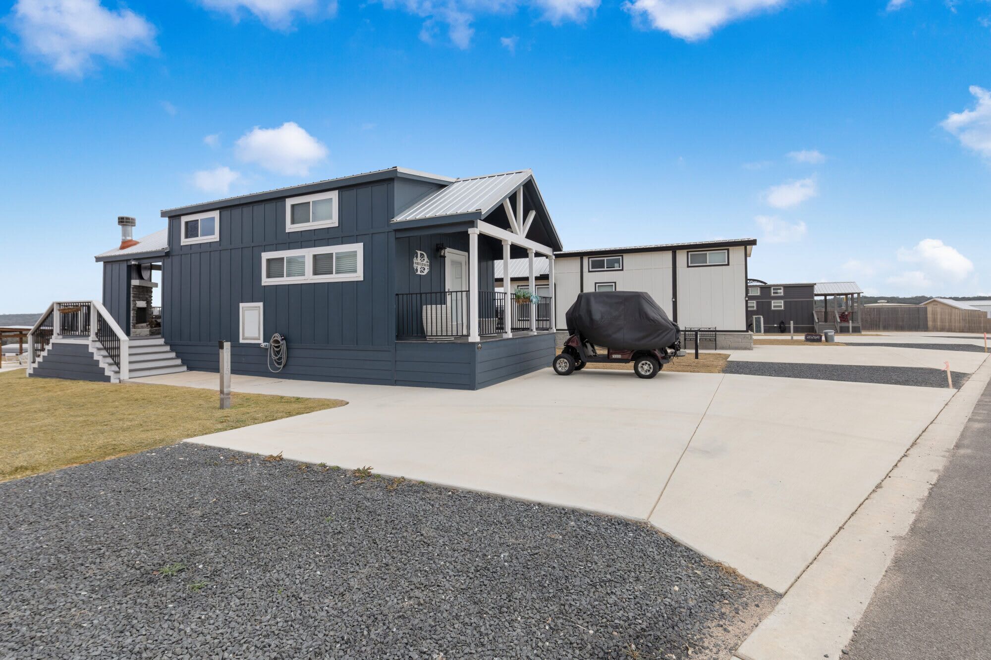 A modern two-story house with a covered porch and a barbecue grill parked outside.