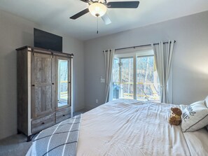 Ein Schlafzimmer mit Bett, Deckenventilator, Kleiderschrank und Fenster mit Vorhängen.