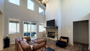 A spacious living room with a fireplace, leather sofas, and a large TV. - Hideout in Blue Ridge (Morganton)