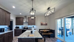 A modern kitchen with granite countertops, dark wood cabinets, and a central island with bar stools. - Hideout in Blue Ridge (Morganton)