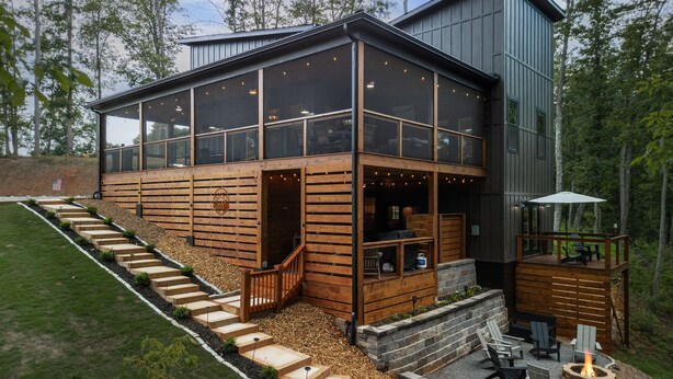 Una casa moderna de dos pisos con amplios ventanales, una terraza y una chimenea.